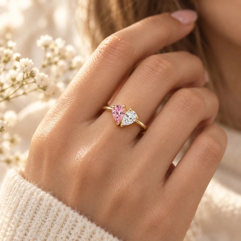 Gold Elara heart ring with pink and clear birthstones, worn on a hand